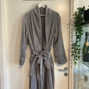 Grå morgonrock oanvänd nypris 449kr - Mysig grå morgonrock med långa ärmar, två stora fickor och knytskärp i midjan. Perfekt för att chilla hemma eller efter duschen. Klassisk och enkel design med avslappnad passform. Oanvänd nypris 449kr 