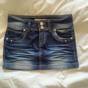 Jeanskjol - Säljer en mörkblå jeanskjol med snygga slitningar och dubbla knappar framtill. Kjolen är jättefin till sommaren och passar till alla situationer. Kjolen finns inte någon annan stans att köpa. Storleken är xs alltså 32-34. Inga defekter.