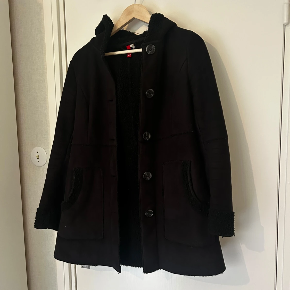 Svart kappa med knappar och teddyfoder