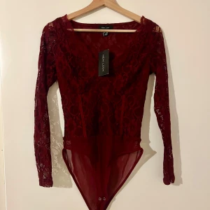 Vinröd spetsbody - Snygg body i spets. Helt ny. Storlek 40, men är lite mindre i storleken, mer som 38.