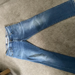 Blå jeans från Jacob Cohen - Säljer ett par klassiska blå jeans från Jacob Cohen. Jeansen har normal passform, fem fickor och stängs med knappar. Perfekta för dig som gillar stilrena och tidlösa jeans.