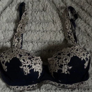 Intimissimi bh  - Säljer en mörkblå bh med vackra beige spetsdetaljer. Bh:n har justerbara axelband och bygel för extra stöd. Perfekt för dig som vill ha något både snyggt och bekvämt.