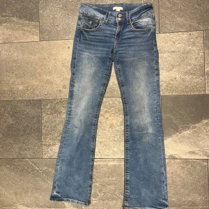 Blå bootcut lågmidjade jeans från Gina Tricot - Säljer ett par klassiska blå bootcut jeans från Gina Tricot med snygga slitningar och dubbla knappar i midjan. Lågmidjade💞💞strl 164
