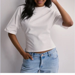 Vit croppad topp med knyt i ryggen - Säljer nu denna tröja från Nelly som man knyter i ryggen, den är super fin men säljer för den tyvärr är för liten för mig vilket är synd, pris kan diskuteras, nypris 250 kr 