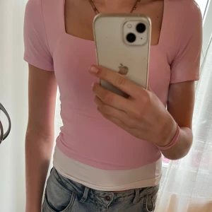 Ljusrosa topp med fyrkantig ringning - Säljer en ljusrosa topp med korta ärmar och snygg fyrkantig ringning. Toppen är figurnära och i mjukt material, perfekt till jeans eller kjol. Enkel och stilren design som passar till många tillfällen.            Tar emot prisförslag ❤️