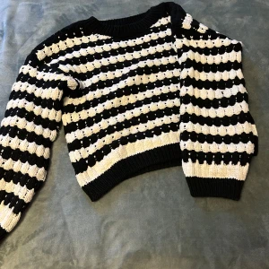 Svartvit randig stickad tröja från Lindex - Säljer en stickad tröja från Lindex i storlek S. Tröjan är svart och vit med ett randigt mönster och har långa ärmar samt ribbade muddar vid hals, ärmslut och nederkant. Jätte bra kvalitet och använd bara enstaka gånger.