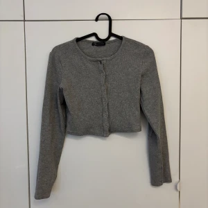 Grå croppad kofta från Zara - Säljer en grå croppad kofta från Zara med långa ärmar och knappar framtill. Använd fåtal gånger.