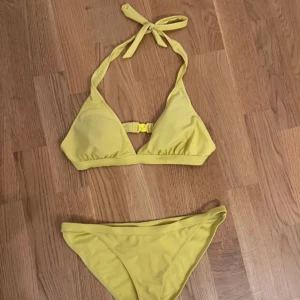 Gul bikini med knyt - Snygg gul bikini med trekantsöverdel som knyts i nacken och spänne i ryggen. Klassiska bikinitrosor med normal passform. Perfekt för sommardagar på stranden eller vid poolen.