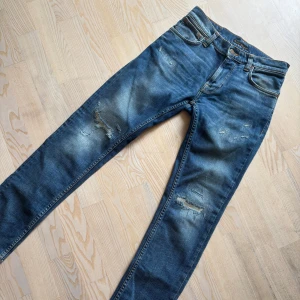 NUDIE JEANS MED SLITNINGAR  - Ett par galet feta nudie ”thin finn” med helt sjuka slitningar som fångar blickar vart man än går. Skicket på jeansen är otroligt fint - ca 9/10. Nypris på sådana här speciella jeans ligger runt 2000kr, vilket gör vårat pris till en helt sjuk deal! Storlek är 28/30 passar även 31 i längd och 29 i midja! Har ni frågor eller funderingar så är det bara att höra av sig!