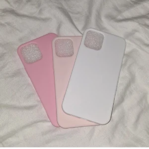 Tre mobilskal i olika färger - Säljer tre stilrena mobilskal i färgerna rosa, ljusrosa och vit. Skalen har en enkel design och är perfekta för att skydda din mobil med en snygg look.