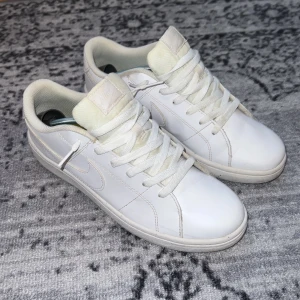 Vita Nike sneakers - Säljer ett par klassiska vita Nike sneakers med låg profil. Jag har använt dem, dem har lite syn på användning men annars är dem i princip nya ut. Perfekta för en clean och stilren look.