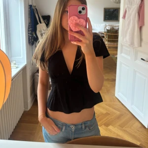 Svart v-ringad blus från Gina tricot  - Säljer en svart blus med djup v-ringning, toppen har korta ärmar och knytning i ryggen.Använd några gånger!!💕