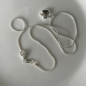 Halsband med hjärthänge i silver 925 - Säljer ett halsband i äkta silver  metall med ett litet hjärta som hänge.  Perfekt för dig som gillar enkla och klassiska smycken.