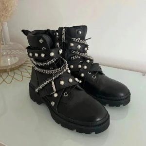 Svarta boots från Zara - Säljer ett par svarta boots från Zara med coola silverfärgade kedjor och pärlor. Mycket bra skick då de knappt är använda, kan sänka pris vid snabb affär!!