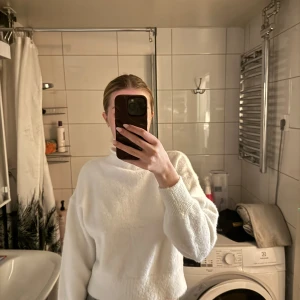 Vit croppad stickad tröja - Säljer en vit croppad stickad tröja med hög hals och långa ärmar. Tröjan har en enkel och stilren design, perfekt för lager-på-lager och passar till många olika outfits.