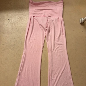 Ljusrosa utsvängda byxor - Säljer ett par ljusrosa byxor med hög midja och utsvängda ben. Byxorna är i ett mjukt och stretchigt material, perfekta för en avslappnad och trendig look.