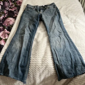 Blå bootcut jeans med rå kant - Säljer ett par blå bootcut jeans från Bershka. Jeansen är low waist och är perfekt för någon som har korta ben på grund av att jag har klippt där nere och man kan se de på bild 3💕