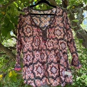 Mönstrad blus från Odd Molly - Säljer en boho-inspirerad blus med lång ärm och v-ringning från Odd Molly. Blusen har ett detaljerat geometriskt mönster i rosa, lila och svart, samt spetsdetaljer vid halsen och små volanger vid ärmsluten. Perfekt för dig som gillar färg och unika prints!Storlek 3 som enligt deras storleksguide motsvarar en storlek L. Kan vara något liten i storlek.  Mycket fint skick, jag hittar inga synliga anmärkningar eller defekter. 