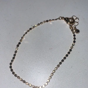 Tunt guldarmband med cirklar - Supersnyggt och minimalistiskt armband i guld med små, blanka cirklar längs hela kedjan. Perfekt för dig som gillar diskreta detaljer och vill ha något som glittrar lite extra på handleden. Justerbar längd med flera ringar vid låset.