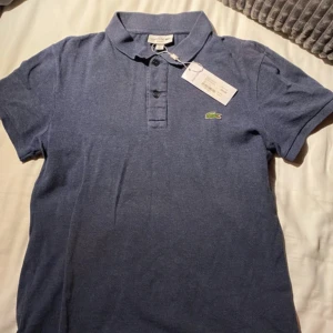 Blå pikétröja från Lacoste - Säljer nu denna Lacoste pike då den är för kort. Använd 2 gånger och prislappen på bilden är borttagen. Hör gärna av vid fler funderingar 