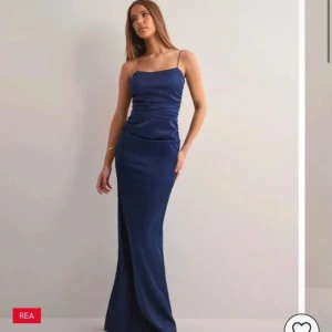Marinblå långklänning med smala axelband - Säljer en elegant marinblå långklänning med smala axelband och figurnära passform. Klänningen har en snygg öppen rygg och är tillverkad i ett glansigt satinliknande material som ger en lyxig känsla. Perfekt för dig som vill sticka ut med en stilren look. Aldrig använd med prislapp kvar💕