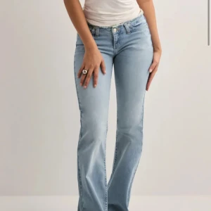 Bootcut ljusblå jeans med rå kant - Snygga ljusblå bootcut jeans med rå, fransad kant upptill. Klassisk femficksmodell med dragkedja och knapp. Jeansen har en låg midja och är tillverkade i mjukt denim som sitter skönt. Perfekta för dig som gillar en chill och trendig look. Använda 3-4 gånger.