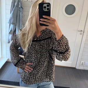 Leopardmönstrad blus☺️💕 - Säljer en blus med leopardmönster i beige och svart. Blusen har långärmade, lätt puffiga ärmar och svarta dekorband över bröstet och vid ärmsluten..