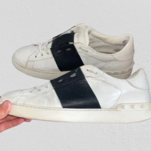 Valentino Open sneakers vit/svart skinn - Snygga Valentino Open sneakers (säljs otroligt mycket kopior på plick men dessa är självklart äkta) i vitt skinn med bred svart läderdetalj över vristen. Klassisk rund tå, platt sula och diskret logga på plösen. Lite målade med vit skofärg av tidigare ägare men det är inget som man tänker på. (OBS sulorna är bytta för bättre kvalitet men det är inget som syns eller har någon påverkan). Suveräna skor, bara att höra av sig om minsta fundering.😁