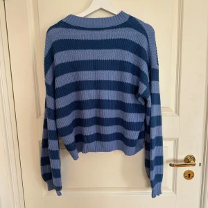 Randig blå stickad tröja från SHEIN - Säljer en chill stickad tröja från SHEIN i storlek S. Tröjan har breda horisontella ränder i två olika blå nyanser och är ribbstickad med rund hals. Perfekt för dig som gillar comfy och snygg stil med lite oversized känsla.