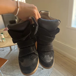 !!!INTRESSEKOLL!!! Svarta sneakers Isabel Marant strl 38 - Coola svarta sneakers från Isabel Marant med chunky design och breda kardborreband. Skorna har en mix av mocka och skinn, rund tå och beige sula. Perfekta för dig som vill ha en statement-sneaker med streetkänsla. 
