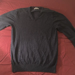 Mörkblå v-ringad tröja Accent - Snygg mörkblå v-ringad tröja från Accent i storlek L. Tröjan har långa ärmar och en beige armbågslapp på ena ärmen som ger en cool touch. 