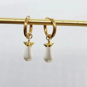 Guldiga örhängen med droppformad pärla - Snygga örhängen i guldton med droppformade vita pärlor som hänger från små ringar. Pärlorna har en cool detalj med guldfärgad topp. Perfekta för att lyfta din stil med en elegant touch.