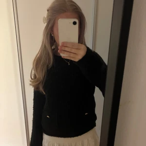 Svart stickad tröja med fickor - Mysig svart stickad tröja med långärmad design och två framfickor med små guldfärgade detaljer.  Använd några gånger. 