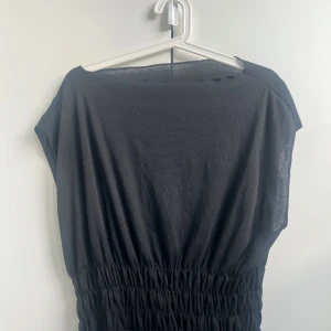 Svart T-shirt liknande  - Svart topp med en pösig överdel med en lite tajtare nere i storlek l