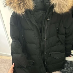 Svart dunjacka Sparrow med äkta päls - Jag köpte denna jacka för 3 år sedan, men den är fortfarande i nyskick. Superfin och väldigt skön att ha på sig. Den håller värmen otroligt bra – det är nästan omöjligt att frysa i den. Jag har använt den max 5 gånger. Pälsen är mjuk, fin och av riktigt bra kvalitet.  (Köpt för 3 999kr)