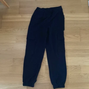 Svarta cargopants från Vero Moda - Svarta cargopants från Vero Moda i storlek S. Byxorna har elastisk midja och muddar vid bensluten, samt stora sidofickor med lock. Perfekta för en chill och avslappnad stil.