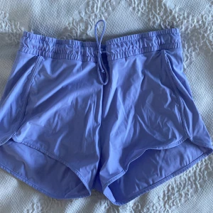 Ljuslila badshorts med snörning - Snygga ljuslila badshorts från Stadium med elastisk midja och snörning framtill. De har en loose passform och inbyggda . Perfekta för bad! Sidoslitsar ger extra rörelsefrihet.