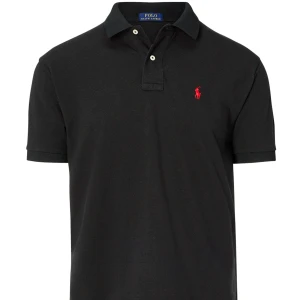 Svart Polo Ralph Lauren t-shirt M - Svart t-shirt från Polo Ralph Lauren i custom slim fit med klassisk krage och två knappar. Ikonisk röd broderad logga på bröstet. Tillverkad i mjuk bomull som känns skön mot huden. Perfekt för dig som gillar stilren och enkel design.