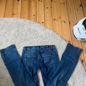 Blå bootcut jeans från LTB W26 L34 - Snygga blå jeans från LTB med bootcut passform. Klassisk femficksmodell med dragkedja och knapp framtill. Jeansen är i stretchigt bomullsmaterial och har snygga detaljer på bakfickorna. Perfekta för dig som gillar en tidlös look.