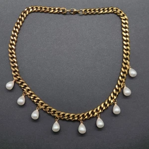 Guldhalsband med pärldroppar - Snyggt halsband i guldton med chunky kedja och sju hängande vita pärldroppar. Perfekt för att ge din outfit en lyxig och trendig touch. Kedjan har ett klassiskt lås och pärlorna ger en elegant vibe.