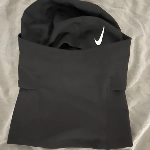 Nike ski mask - Nike Pro Therma-FIT Hood i svart, perfekt för fotboll och träning. Huvan är tillverkad i mjukt och värmande syntetmaterial med Therma-FIT-teknologi. Snygg Nike-logga i vitt framtill och diskret Nike Pro-märke baktill. Slimmad passform som sitter skönt runt huvudet.