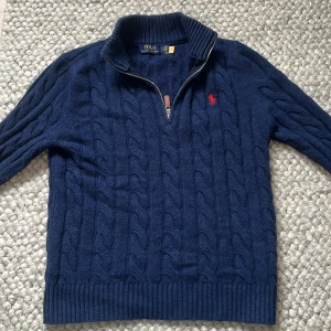 Marinblå stickad halfzip Polo Ralph Lauren🙌 - Säljer en marinblå stickad halfzip från Polo Ralph Lauren med klassiskt kabelstickat mönster och röd logga på bröstet. Tröjan är i storlek S och nästan helt oanvänd 🙌✅