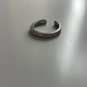 Silverfärgad ring - Säljer en stilren och enkel silverfärgad ring med stjärn design. Perfekt accessoar för att komplettera din stil.