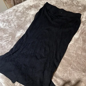 Svart ribbad kjol från STOCKHLM - Snygg svart ribbad kjol från Stockh LM. Kjolen har en elegant och enkel design med en bekväm passform. Perfekt för att matcha med olika toppar och accessoarer.