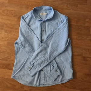 Ljusblå linneskjorta från Dressmann - Säljer en stilren ljusblå skjorta från Dressmann i linneblandning. Skjortan har långa ärmar och knappar framtill. Perfekt för en avslappnad men ändå uppklädd look. Skick: 7/10 Säljer då den är för litenför mig. Storlek S men passar XS.