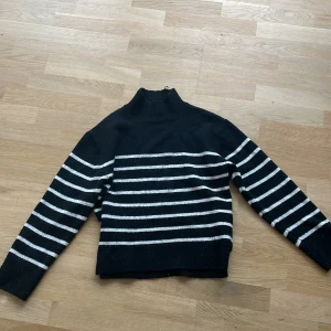 Svart och vit randig tröja från Gina Tricot - Säljer en snygg svart och vit randig tröja från Gina Tricot. Tröjan har en hög krage och långa ärmar, perfekt för kyligare dagar. Den är ribbad vid nederkant för extra komfort. Passar både till jeans och kjol!💞