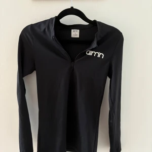 Aim’n - Säljer en svart långärmad tröja från Aim'n i storlek S. Tröjan är tillverkad av 73% polyester och 27% spandex, vilket ger en skön och stretchig passform. 