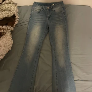 Blå jeans med broderade bakfickor - Snygga blå jeans med en bootcut-stil och broderade detaljer på bakfickorna. Jeansen har en klassisk femficksdesign och en knappstängning fram. Perfekta för en avslappnad look. Köptes från Shein men knappt använd.