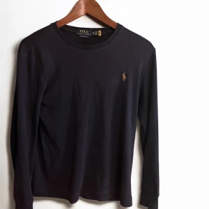  Ralph Lauren tröja  - Säljer en stilren mörkblå långärmad tröja från Polo Ralph Lauren. Tröjan har en broderad logotyp på bröstet och är i en slim fit passform. Priset är inte hugget i sten vid en snabb och smidig affär 