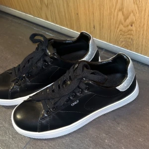 Svarta sneakers  - Säljer dessa helt oanvända sneakers från Only. De är svarta med glansig yta med en silver glitter detalj på baksidan. Storlek 36 men sitter mer som 37. Köpta för ca 450kr på zalando💓 